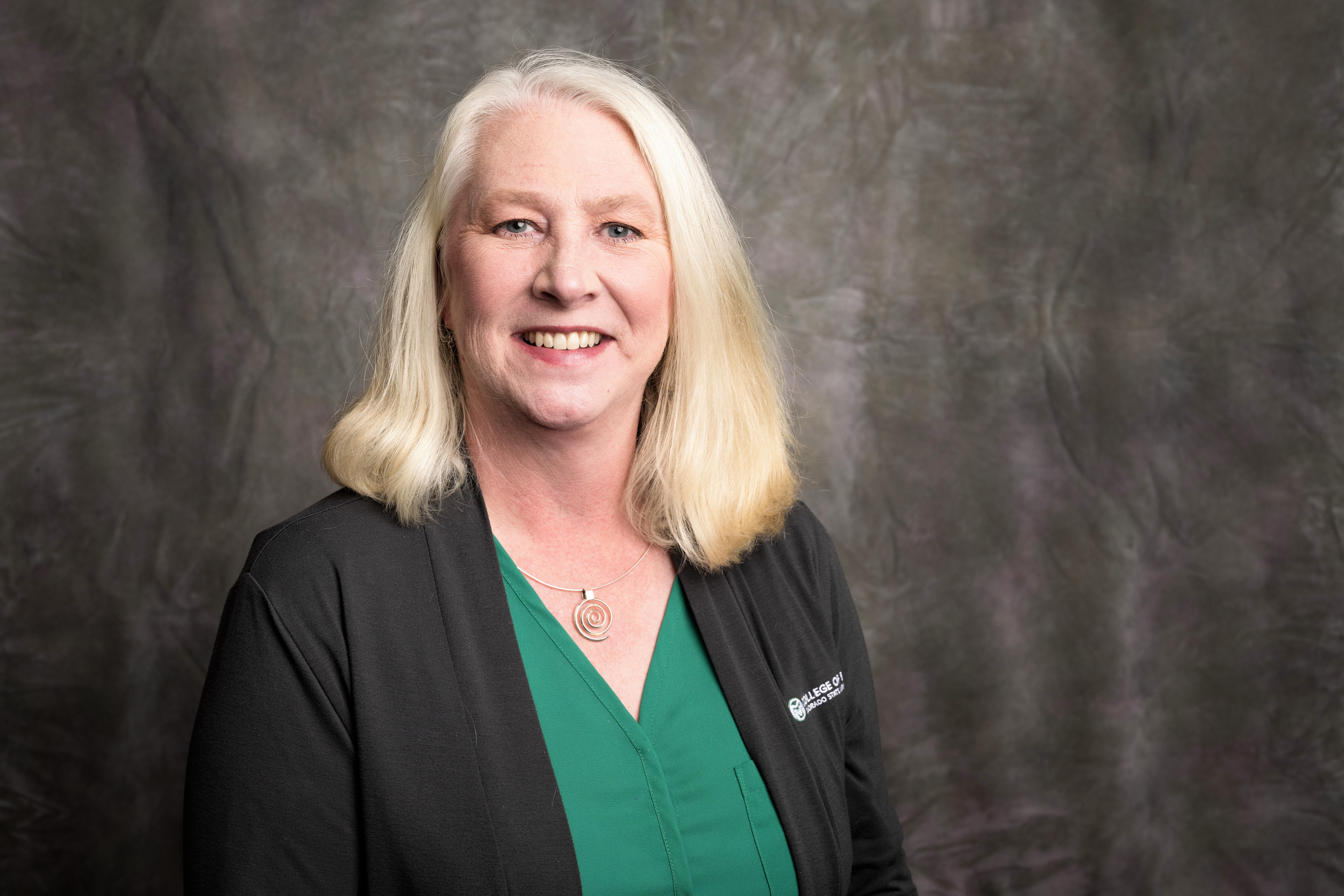 Headshot of Lorie Humphrey, CCDA President, wearing a bright green top and grey cardigan with Colorado State University embroidered on the chest.